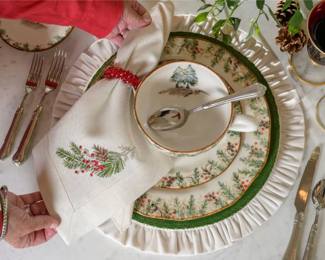 Holiday place setting with evergreen dinnerware and embroidered napkin